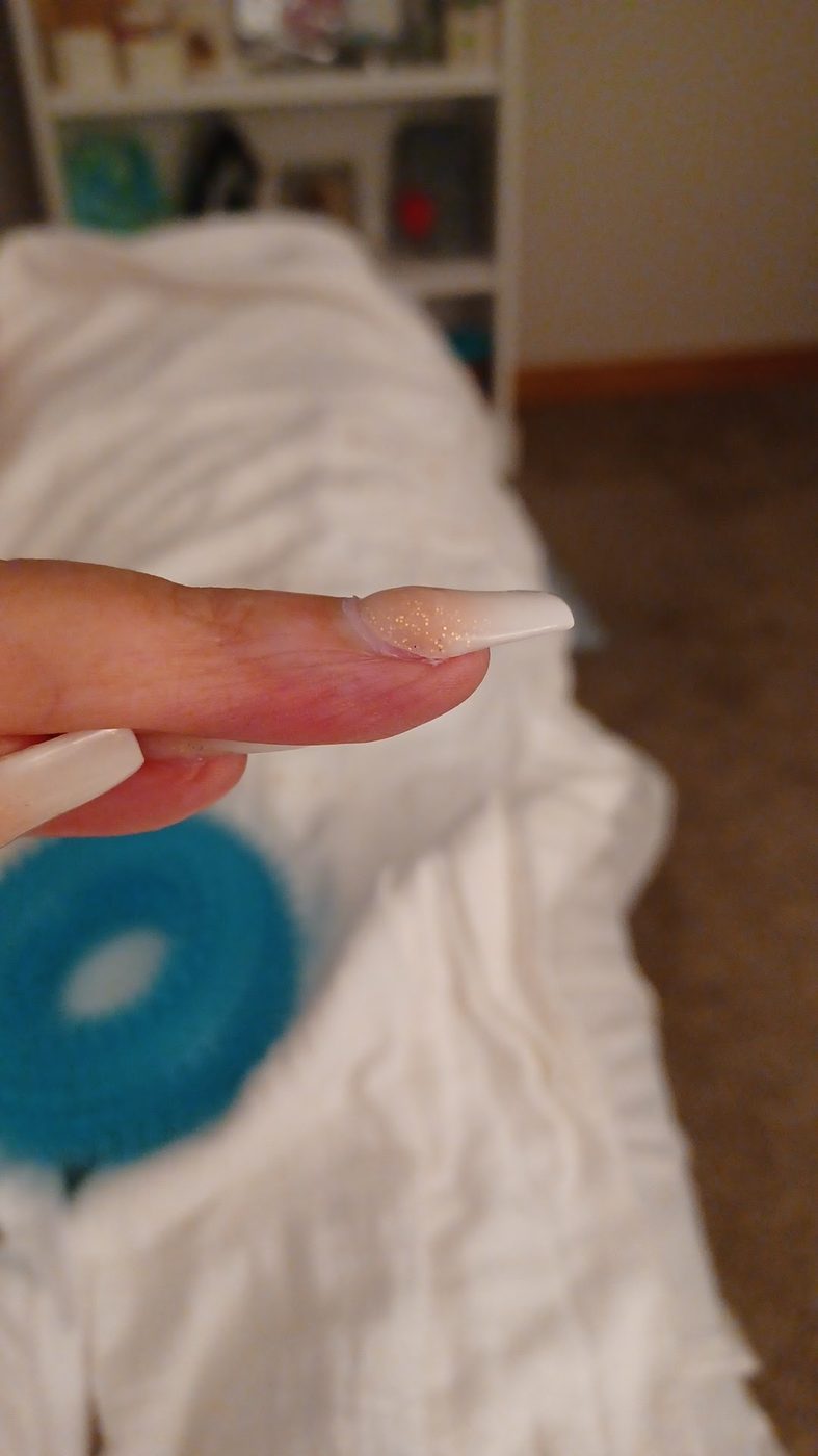 Side view of a French ombré acrylic nail with fine glitter near the cuticle.