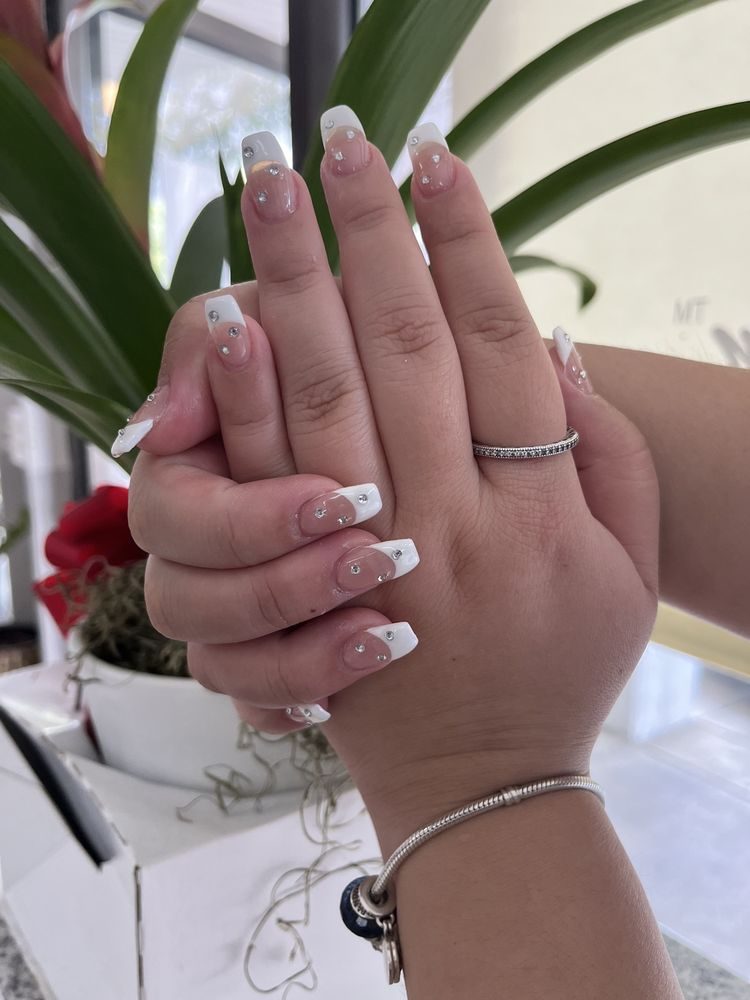 Long French tip nails with silver crystals, photographed in the salon.