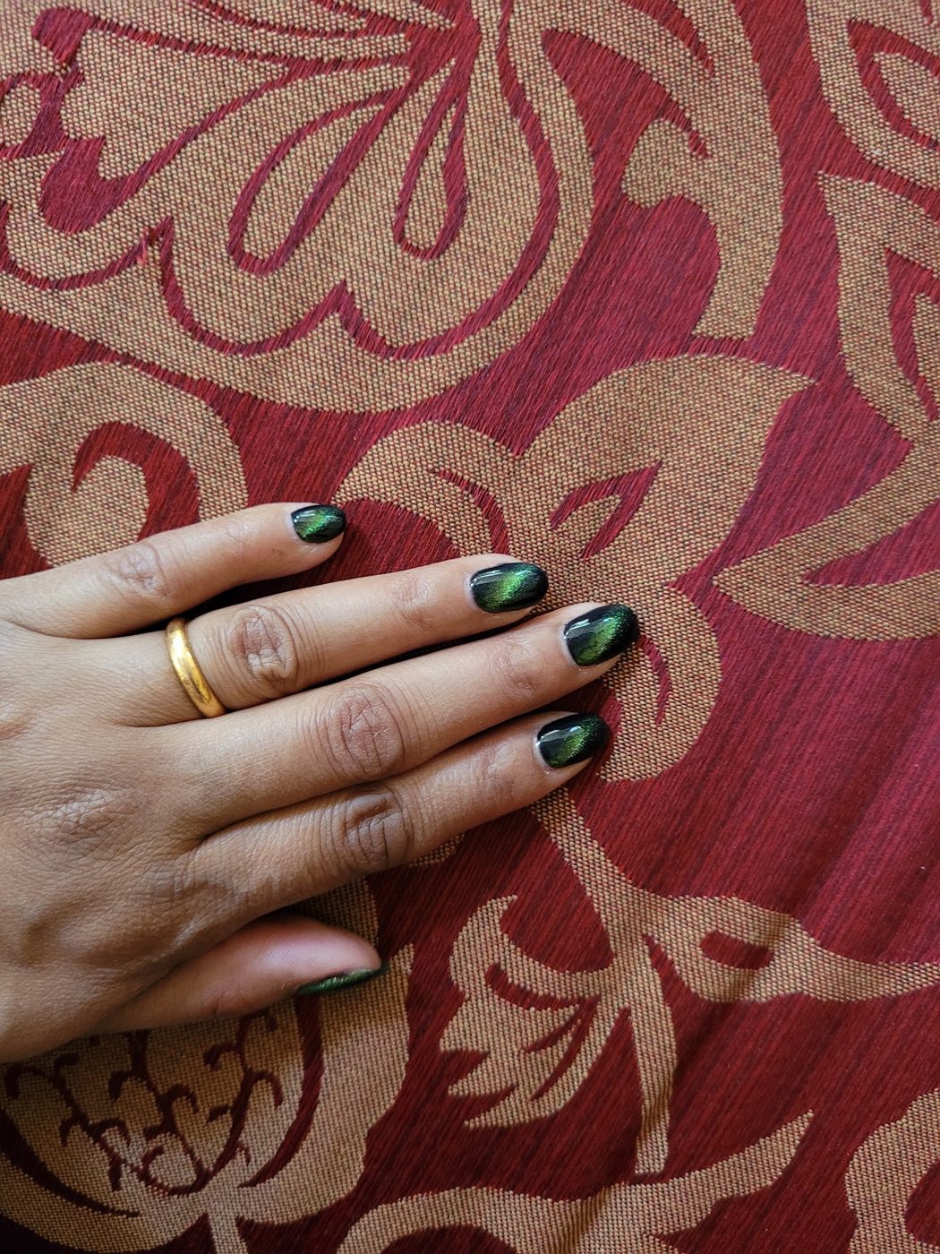 Short oval nails with dark green cat-eye magnetic gel.