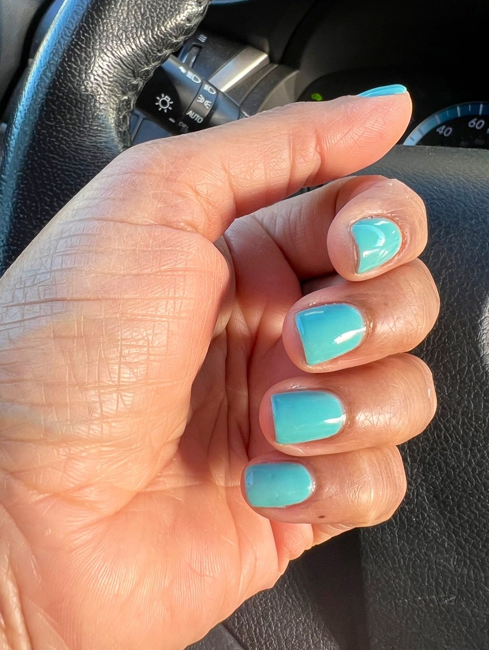 Short square nails in glossy turquoise gel polish.